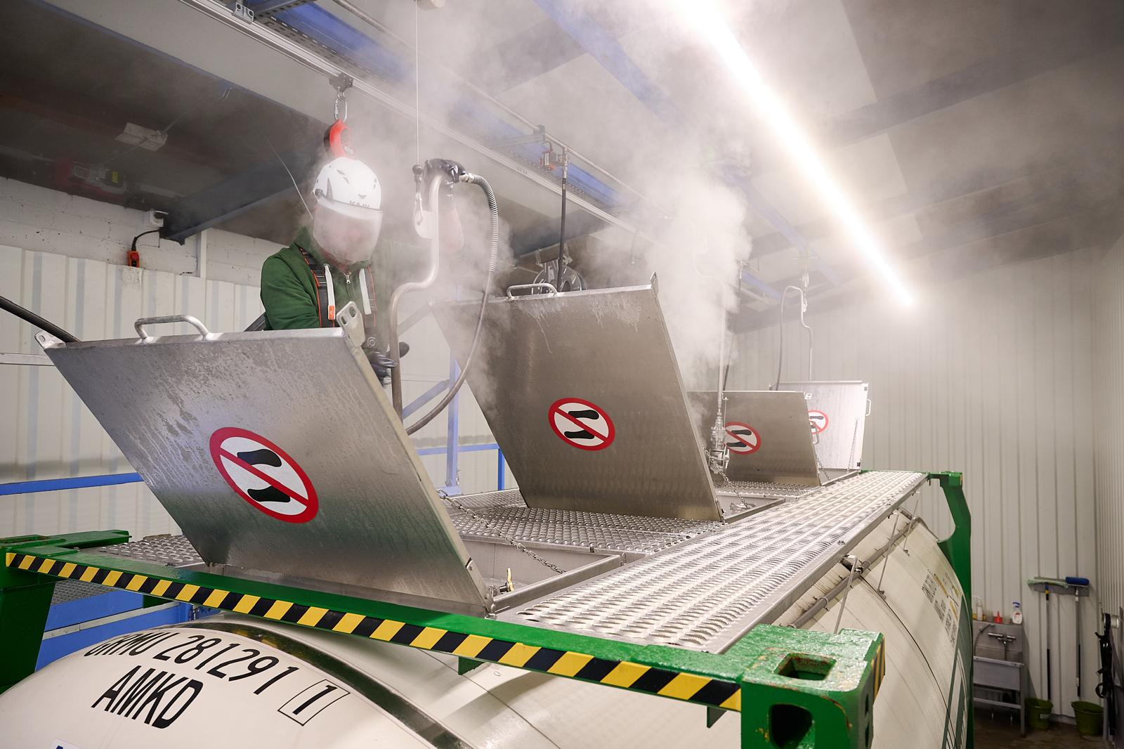 Mitarbeiter öffnet die Domdeckel eines Tankcontainers für die Reinigung